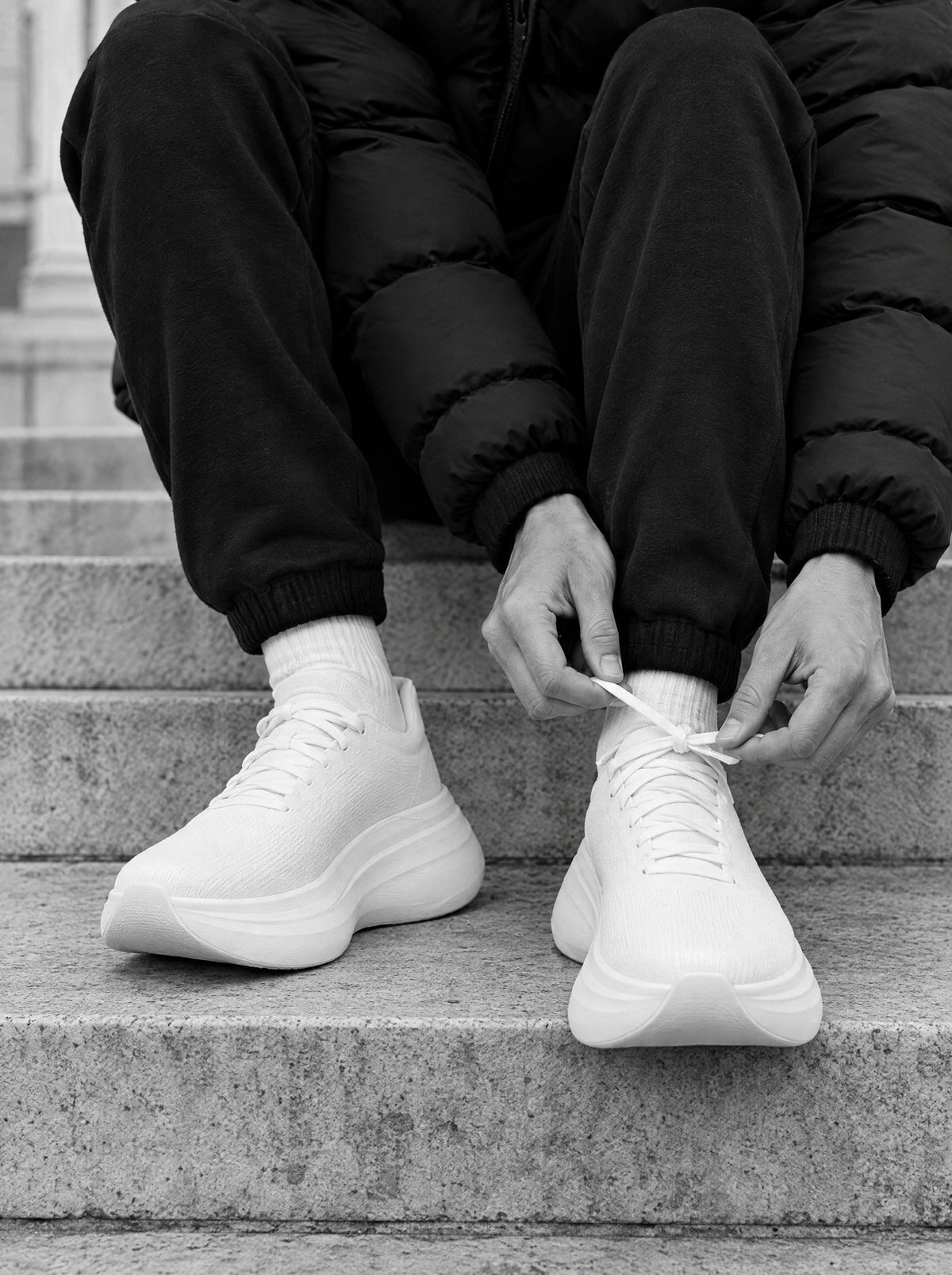 Lacing white cushioned running shoes on stone steps